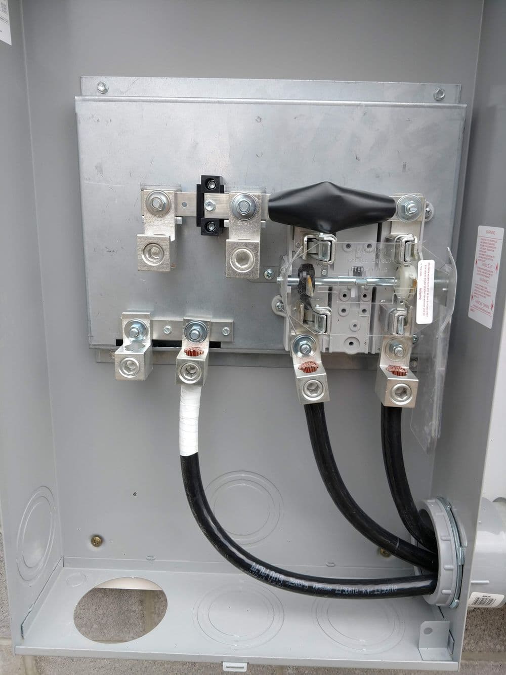 Electric panel showing circuit connections and wiring in a metal enclosure.