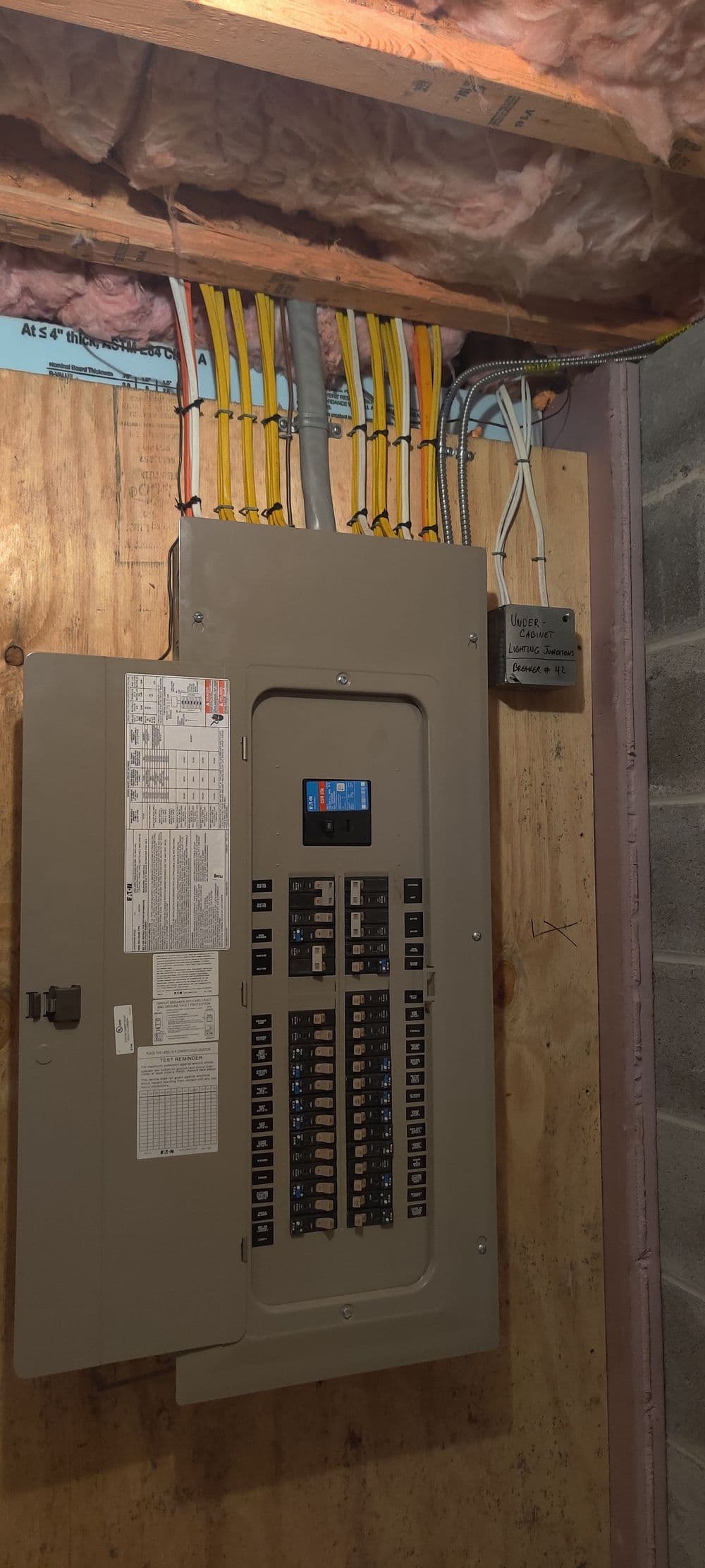 Main electrical panel with circuit breakers and organized wiring in a basement setting.